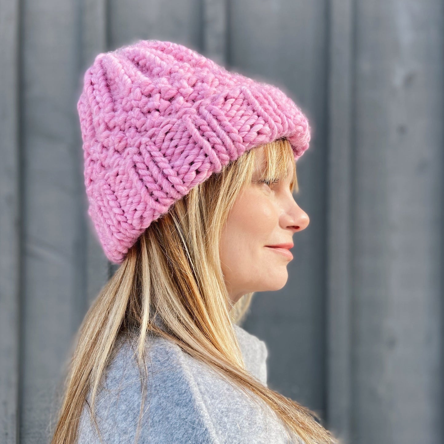 Woman wearing a Ruka brand knitted pink beanie outdoors.